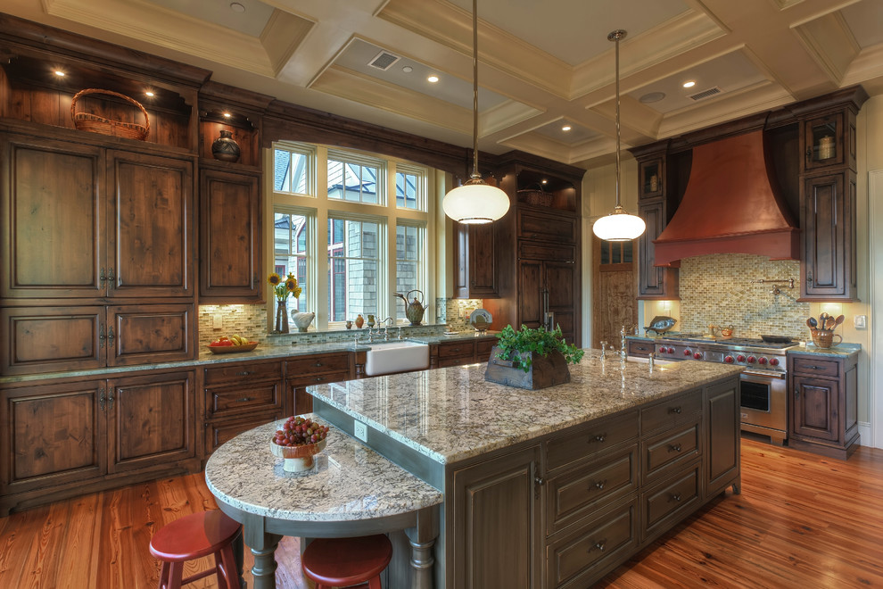 Inspiration for a large timeless l-shaped medium tone wood floor and brown floor eat-in kitchen remodel in Charleston with a farmhouse sink, raised-panel cabinets, dark wood cabinets, granite countertops, multicolored backsplash, glass tile backsplash, paneled appliances and an island