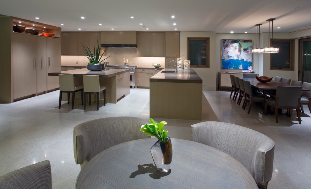 Large modern u-shaped open plan kitchen in Orange County with a submerged sink, flat-panel cabinets, white cabinets, composite countertops, beige splashback, glass sheet splashback, integrated appliances, marble flooring, an island and grey floors.