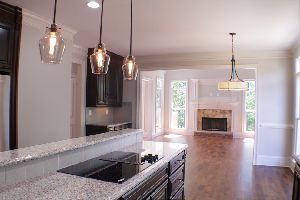 Example of a large arts and crafts u-shaped medium tone wood floor open concept kitchen design in Atlanta with dark wood cabinets, granite countertops, beige backsplash, stainless steel appliances, an island, a double-bowl sink, raised-panel cabinets and terra-cotta backsplash