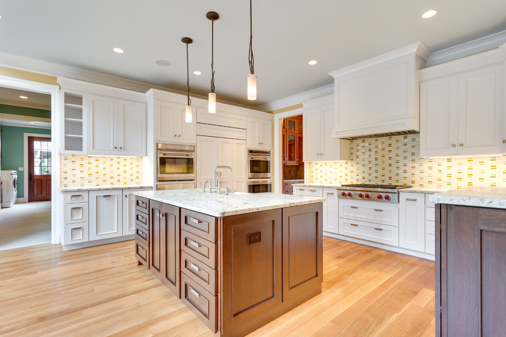 Idéer för ett stort, avskilt amerikanskt vit u-kök, med en rustik diskho, luckor med infälld panel, vita skåp, granitbänkskiva, flerfärgad stänkskydd, stänkskydd i keramik, integrerade vitvaror, mellanmörkt trägolv, en köksö och brunt golv