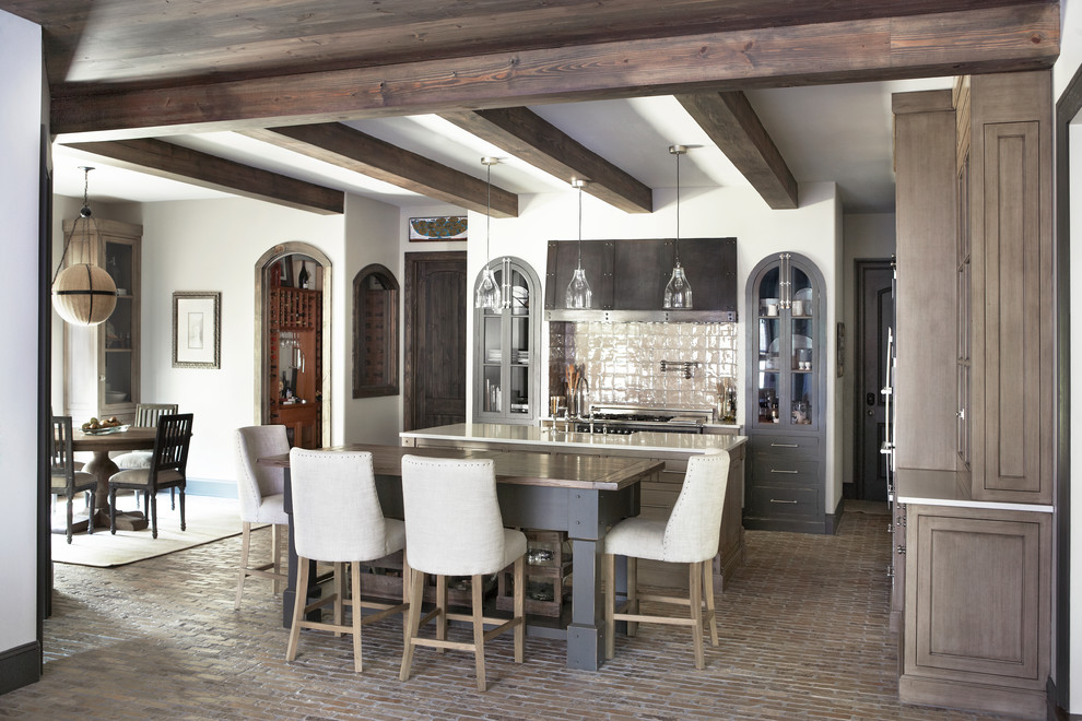 На фото: кухня в классическом стиле с коричневыми фасадами, обеденным столом, кирпичным полом и островом