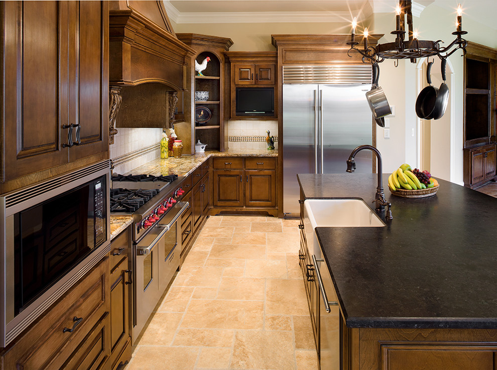 This is an example of a traditional kitchen in Houston with a belfast sink, raised-panel cabinets, dark wood cabinets and stainless steel appliances.