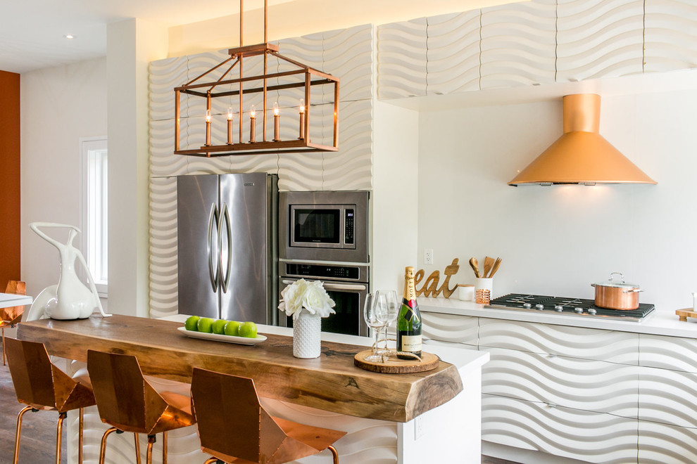 Cette image montre une cuisine américaine design avec des portes de placard blanches, une crédence blanche, un électroménager en acier inoxydable, parquet foncé et îlot.