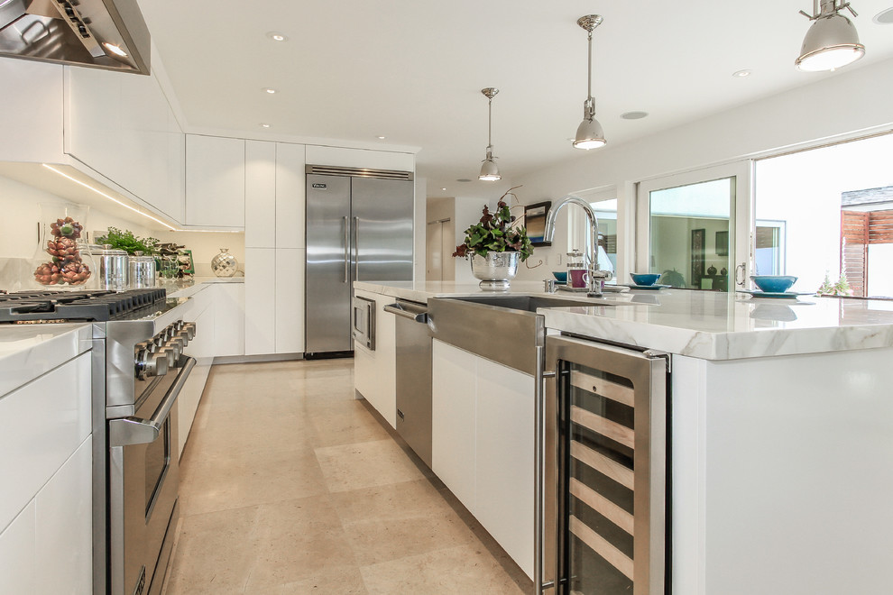 Example of an island style u-shaped eat-in kitchen design in Orange County with a single-bowl sink, flat-panel cabinets, white cabinets, marble countertops, white backsplash and stainless steel appliances