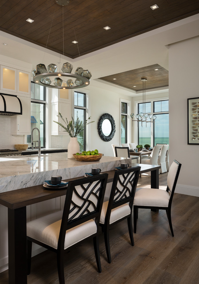 This is an example of a contemporary kitchen/diner in Miami with a submerged sink, white cabinets, white splashback, stainless steel appliances, dark hardwood flooring, an island, brown floors and white worktops.