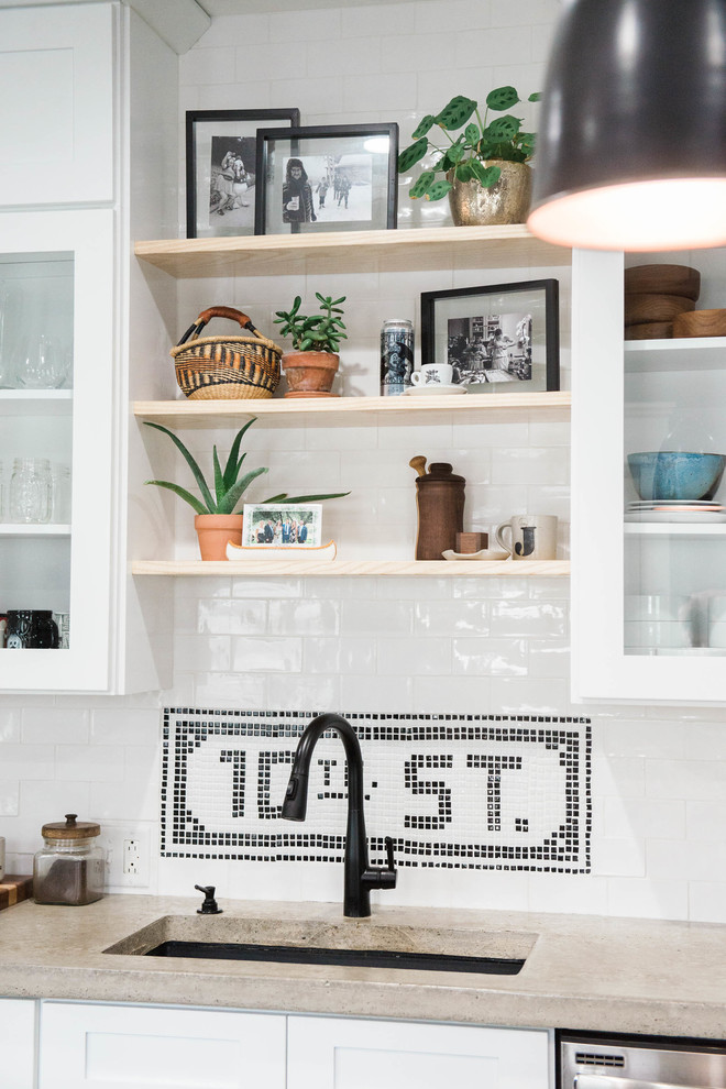 Example of a small eclectic single-wall slate floor and gray floor kitchen pantry design in New York with an undermount sink, glass-front cabinets, white cabinets, concrete countertops, white backsplash, ceramic backsplash, stainless steel appliances and an island