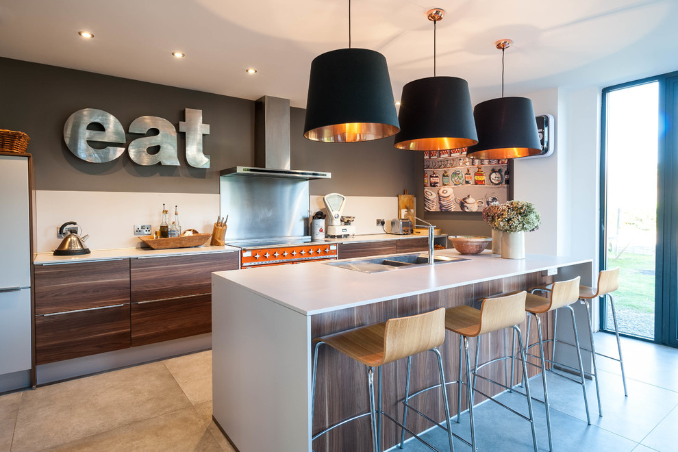 Contemporary galley kitchen in West Midlands with a built-in sink, flat-panel cabinets, dark wood cabinets, coloured appliances, an island and grey floors.