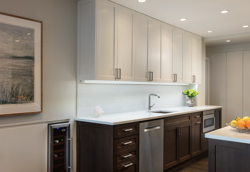 Inspiration for a small modern galley open plan kitchen in New York with a submerged sink, shaker cabinets, dark wood cabinets, engineered stone countertops, white splashback, ceramic splashback, stainless steel appliances, dark hardwood flooring, no island, brown floors and white worktops.