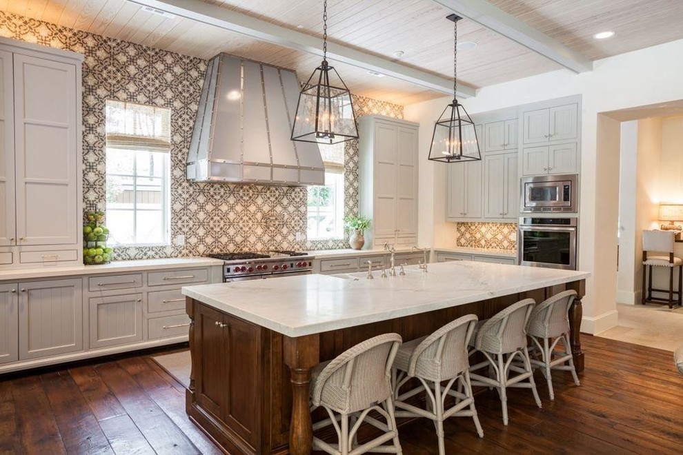 Klassisk inredning av ett l-kök, med luckor med infälld panel, grå skåp, flerfärgad stänkskydd och rostfria vitvaror