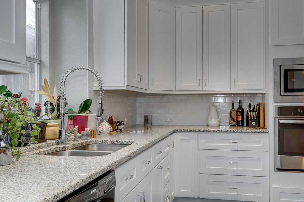 Photo of a medium sized classic l-shaped kitchen/diner in Dallas with a submerged sink, shaker cabinets, white cabinets, granite worktops, white splashback, metro tiled splashback, stainless steel appliances, porcelain flooring and an island.