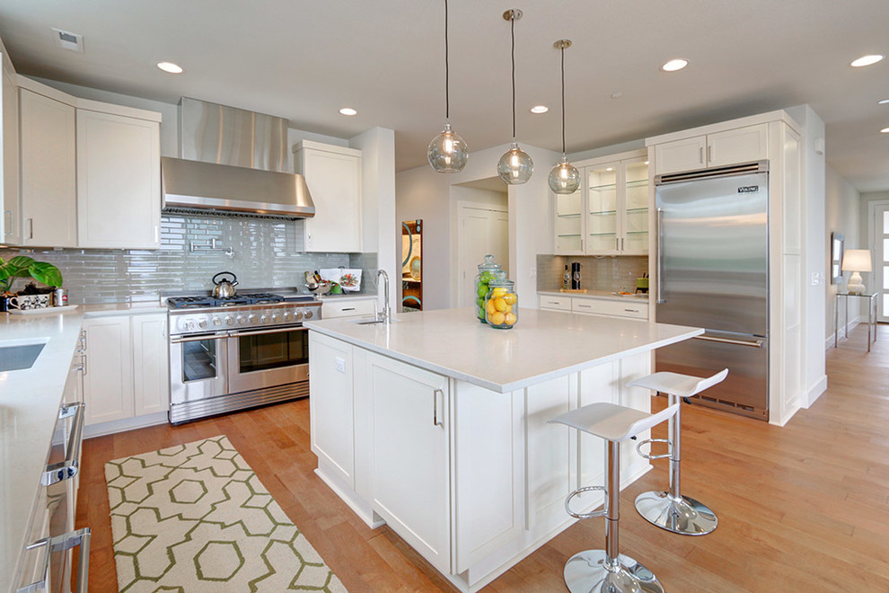 Moderne Küche mit Unterbauwaschbecken, Schrankfronten im Shaker-Stil, weißen Schränken, Küchenrückwand in Grau, Küchengeräten aus Edelstahl, hellem Holzboden und Kücheninsel in Seattle