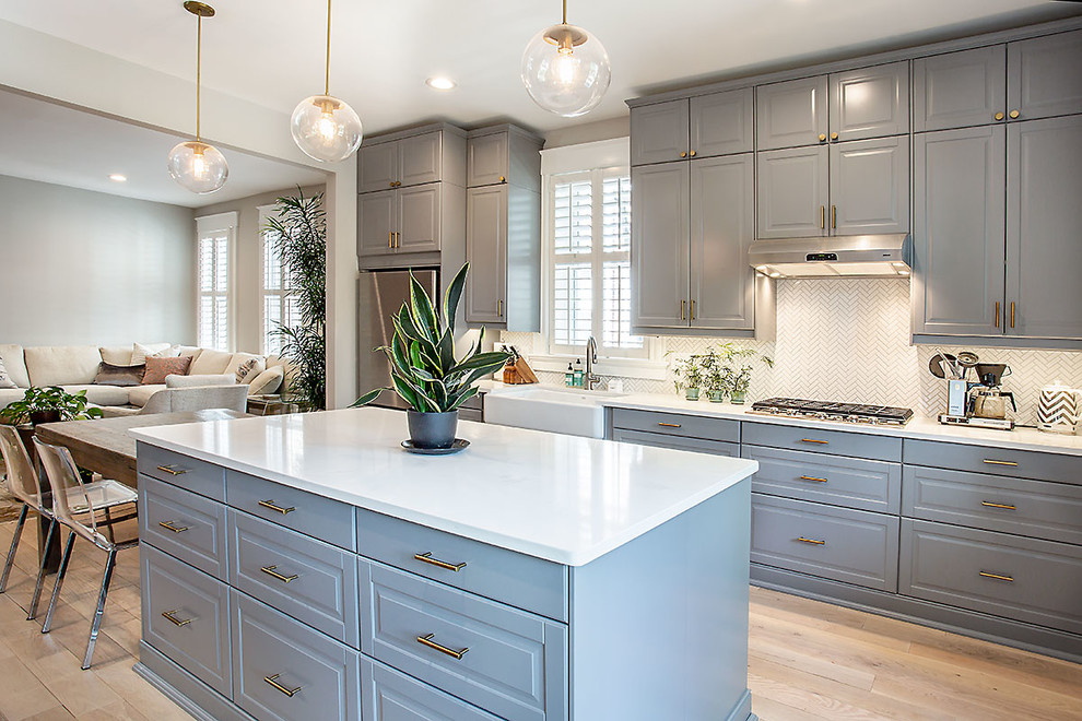 Large elegant light wood floor and beige floor open concept kitchen photo in Richmond with a farmhouse sink, quartz countertops, white backsplash, ceramic backsplash, stainless steel appliances, an island, white countertops, raised-panel cabinets and blue cabinets