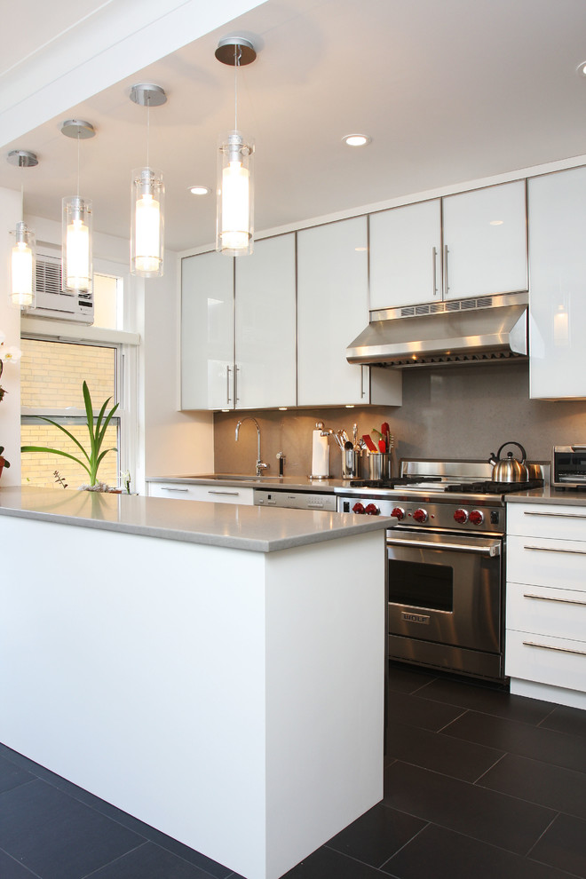 Cette photo montre une cuisine linéaire tendance avec un placard à porte plane, des portes de placard blanches, une crédence marron, un électroménager en acier inoxydable et une péninsule.