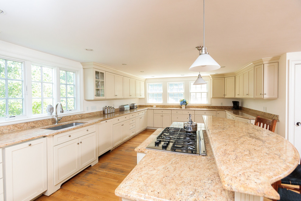 Design ideas for a large classic l-shaped open plan kitchen in Boston with a built-in sink, beaded cabinets, white cabinets, granite worktops, beige splashback, stainless steel appliances, medium hardwood flooring, an island and beige worktops.