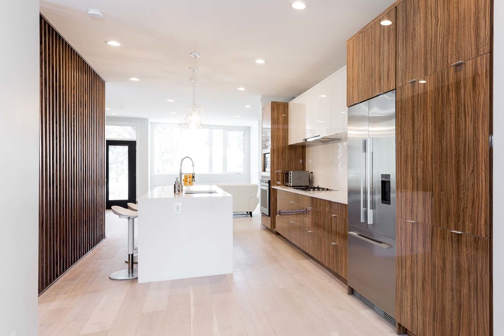 Example of a mid-sized trendy single-wall light wood floor eat-in kitchen design in Edmonton with an undermount sink, flat-panel cabinets, granite countertops, white backsplash, stainless steel appliances and an island