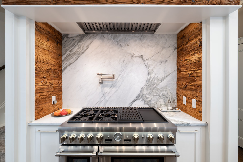 Exempel på ett stort klassiskt vit vitt kök, med en undermonterad diskho, luckor med profilerade fronter, vita skåp, bänkskiva i kvartsit, vitt stänkskydd, stänkskydd i sten, rostfria vitvaror, mörkt trägolv, en köksö och brunt golv