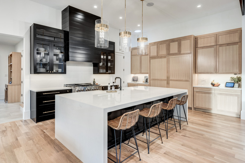 Exempel på ett modernt vit vitt kök, med en rustik diskho, luckor med infälld panel, svarta skåp, bänkskiva i kvarts, vitt stänkskydd, stänkskydd i marmor, rostfria vitvaror, ljust trägolv, en köksö och brunt golv
