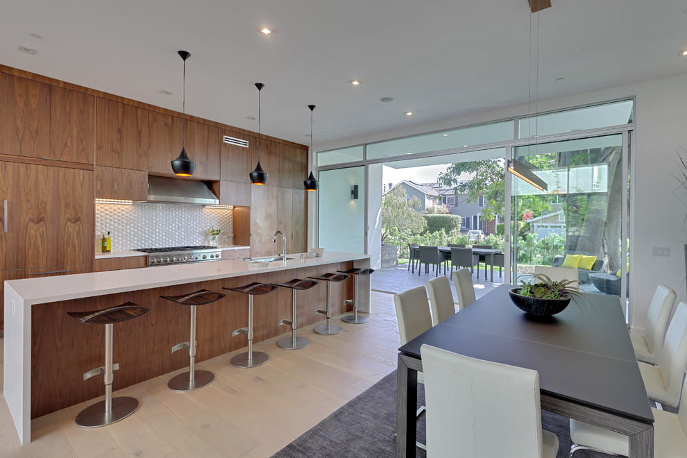 Photo of a contemporary galley kitchen/diner in Los Angeles with a submerged sink, flat-panel cabinets, dark wood cabinets, white splashback, light hardwood flooring and an island.