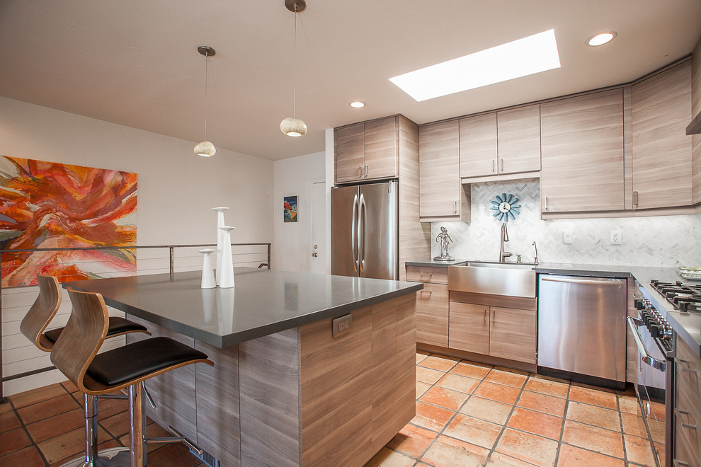 Immagine di una cucina minimalista con ante in legno chiaro, paraspruzzi grigio, elettrodomestici in acciaio inossidabile e pavimento in terracotta