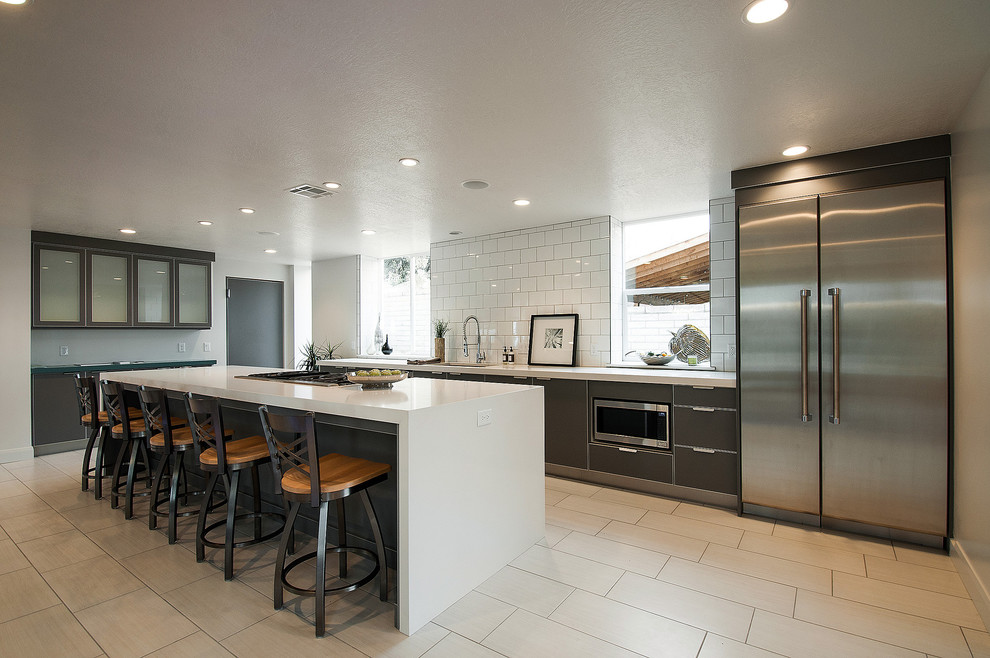 Modelo de cocina contemporánea con armarios con paneles lisos, electrodomésticos de acero inoxidable, puertas de armario marrones, salpicadero blanco y barras de cocina