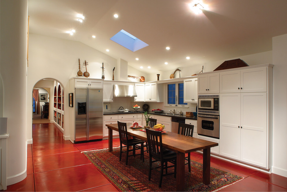 Immagine di una cucina a L mediterranea con elettrodomestici in acciaio inossidabile, ante in stile shaker, ante bianche e pavimento rosso