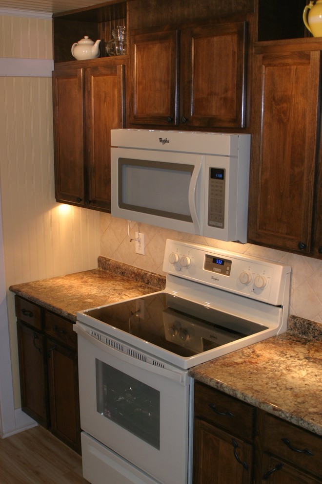 Exempel på ett litet eklektiskt kök, med en dubbel diskho, luckor med infälld panel, laminatbänkskiva, grått stänkskydd, stänkskydd i keramik, vita vitvaror och ljust trägolv