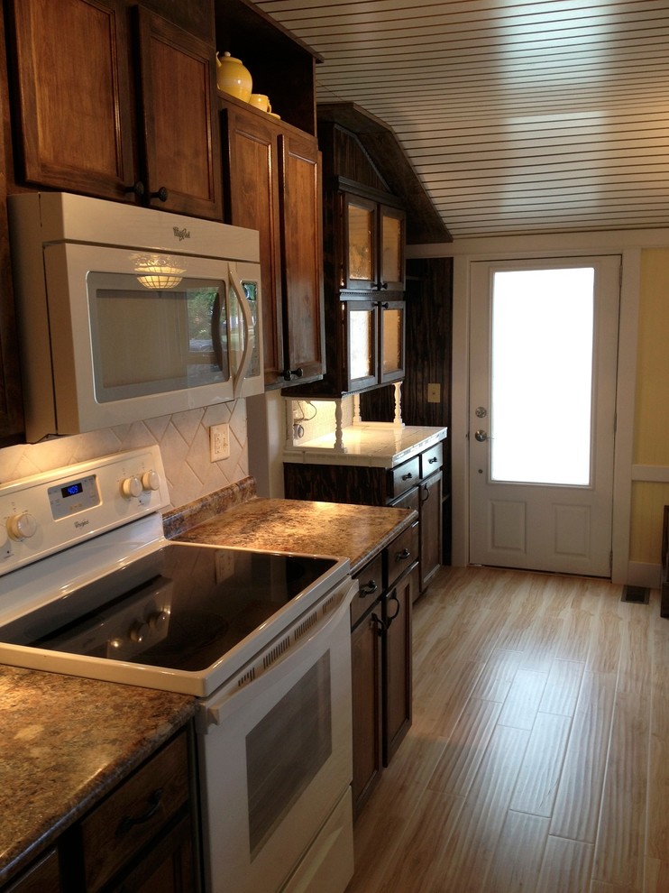 Small traditional galley enclosed kitchen in Cincinnati with a double-bowl sink, dark wood cabinets, laminate countertops, multi-coloured splashback, ceramic splashback, white appliances, light hardwood flooring and no island.