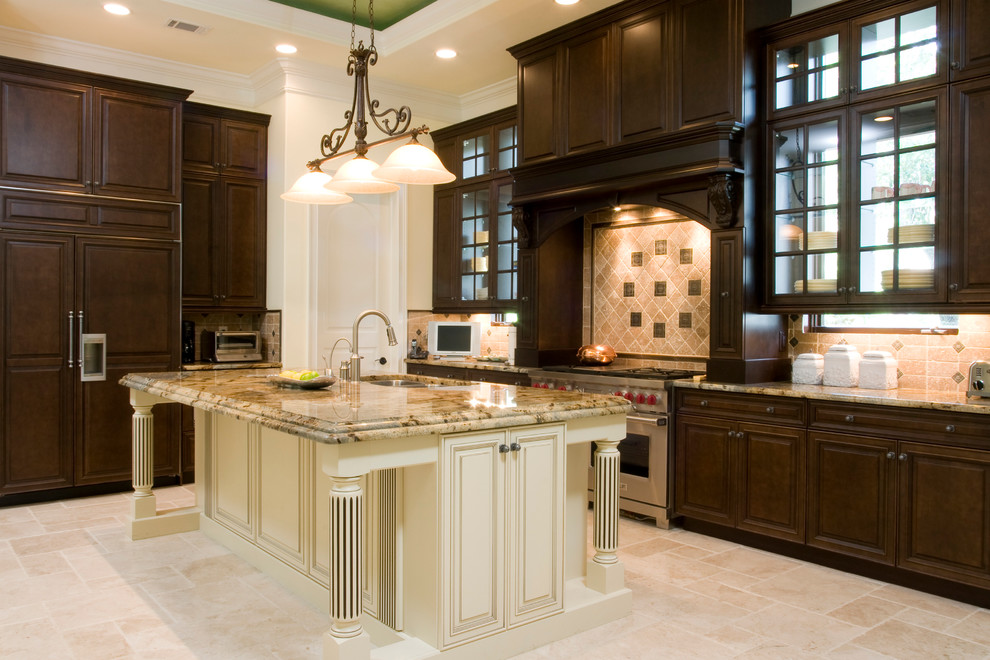 Inspiration for a large mediterranean l-shaped travertine floor open concept kitchen remodel in Charleston with a double-bowl sink, raised-panel cabinets, dark wood cabinets, onyx countertops, beige backsplash, paneled appliances and an island