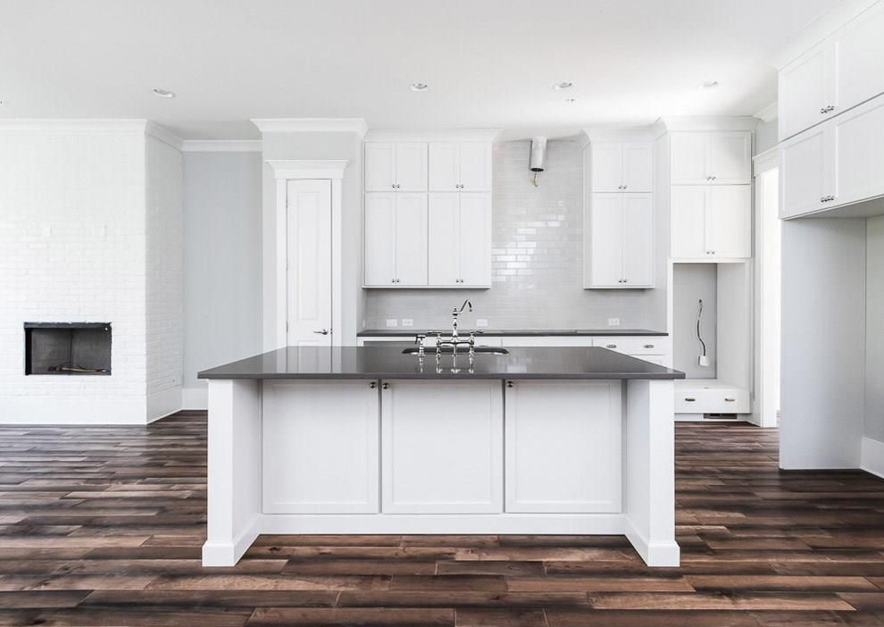 Inspiration for a mid-sized timeless single-wall bamboo floor and brown floor eat-in kitchen remodel in Atlanta with an undermount sink, raised-panel cabinets, white cabinets, laminate countertops, two islands and black countertops