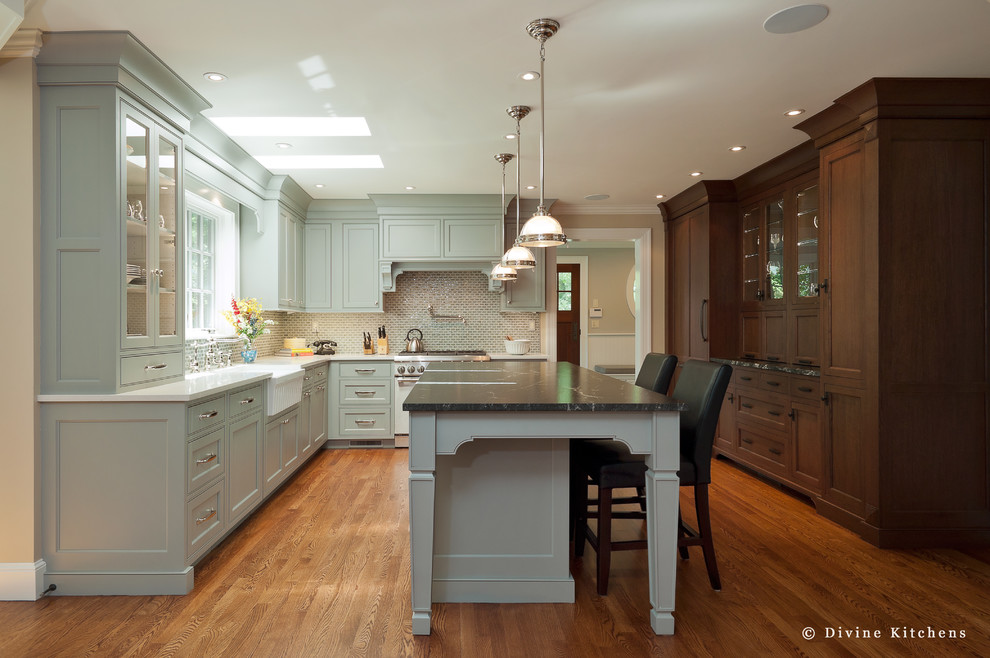 Inredning av ett klassiskt stort kök, med en rustik diskho, luckor med upphöjd panel, vita skåp, beige stänkskydd, rostfria vitvaror, mellanmörkt trägolv och en köksö