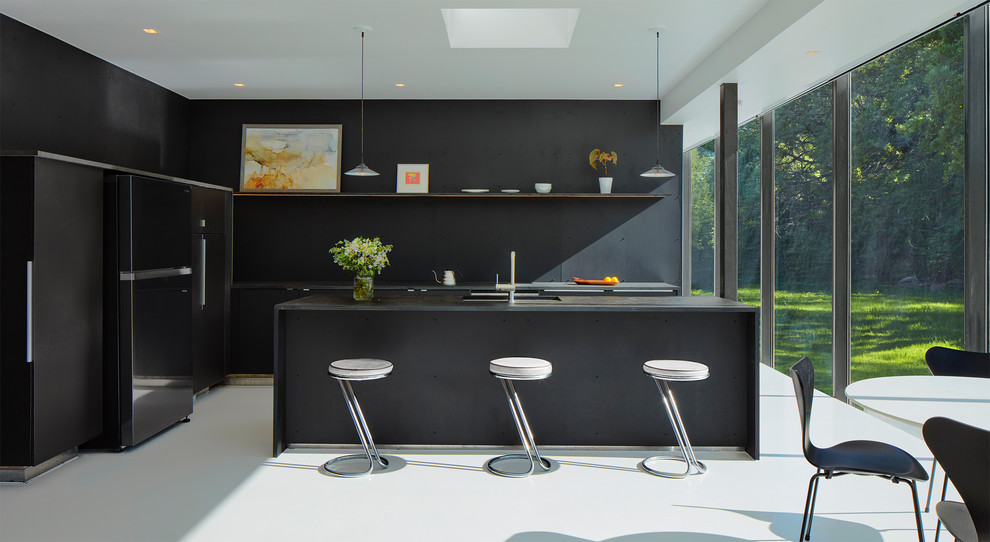 Idee per un cucina con isola centrale minimalista con ante lisce, ante nere, paraspruzzi nero, elettrodomestici neri, pavimento bianco e top nero