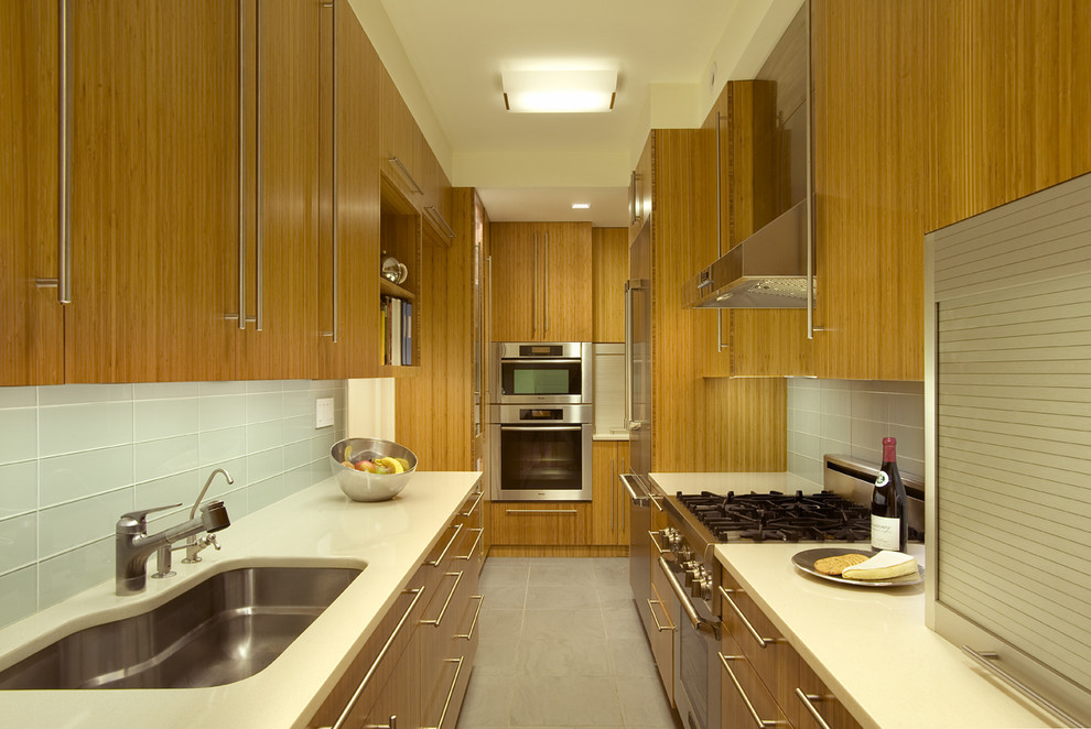 ニューヨークにある中くらいなコンテンポラリースタイルのおしゃれなキッチン (ガラスタイルのキッチンパネル、シルバーの調理設備、アンダーカウンターシンク、白いキッチンパネル、フラットパネル扉のキャビネット、中間色木目調キャビネット、珪岩カウンター、セラミックタイルの床、アイランドなし、グレーの床) の写真