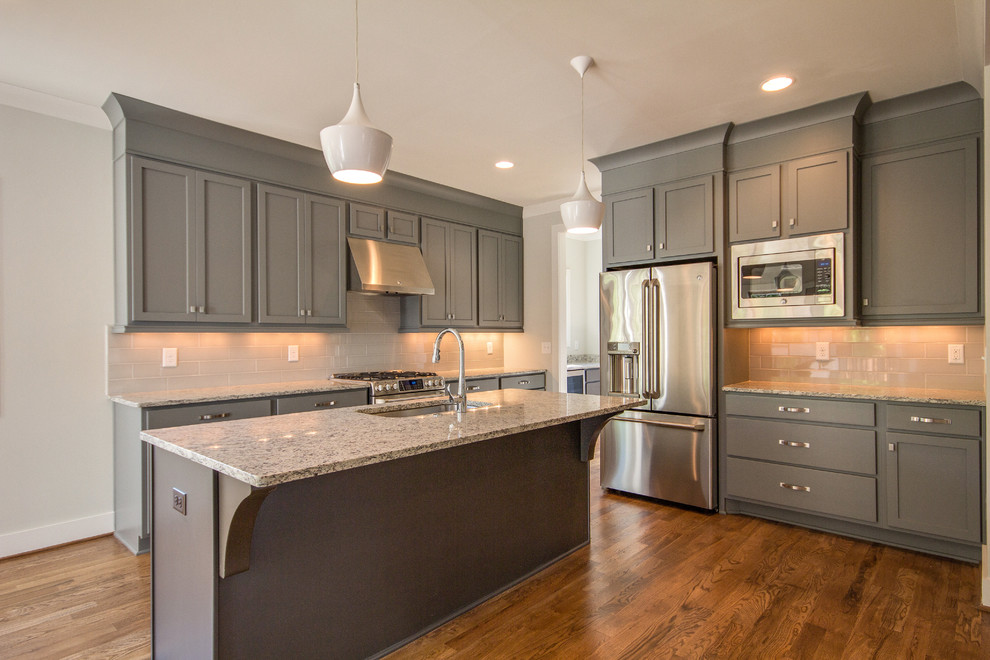 Inspiration for a mid-sized craftsman l-shaped medium tone wood floor open concept kitchen remodel in Nashville with a single-bowl sink, shaker cabinets, blue cabinets, granite countertops, gray backsplash, subway tile backsplash, stainless steel appliances and an island