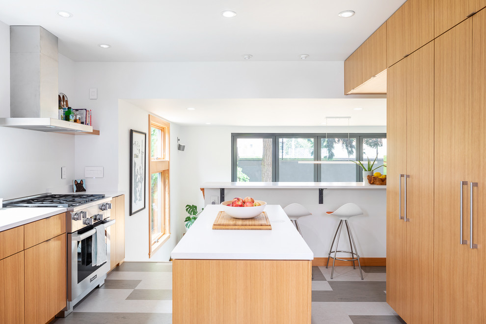 Idee per un cucina con isola centrale moderno con ante lisce, ante in legno chiaro, elettrodomestici in acciaio inossidabile, pavimento multicolore e top bianco