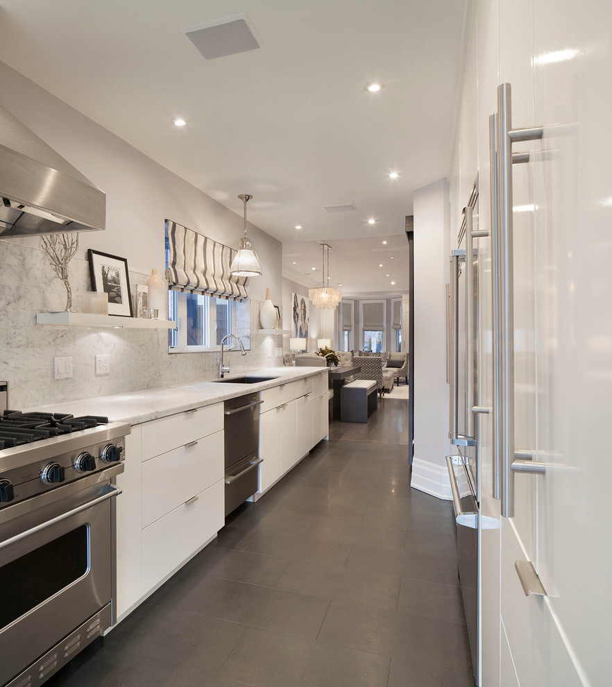 Inspiration for a traditional galley enclosed kitchen in Toronto with a submerged sink, flat-panel cabinets, white cabinets, white splashback and stainless steel appliances.