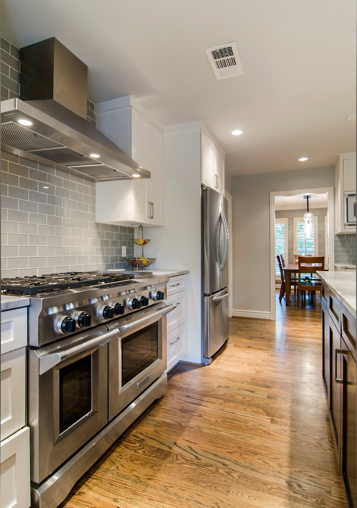 Inspiration for a transitional u-shaped eat-in kitchen remodel in Dallas with an undermount sink, shaker cabinets, white cabinets, granite countertops, gray backsplash, glass tile backsplash and stainless steel appliances