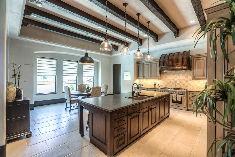 Example of a large tuscan l-shaped limestone floor and beige floor open concept kitchen design in Houston with an undermount sink, raised-panel cabinets, medium tone wood cabinets, granite countertops, beige backsplash, mosaic tile backsplash, paneled appliances and an island