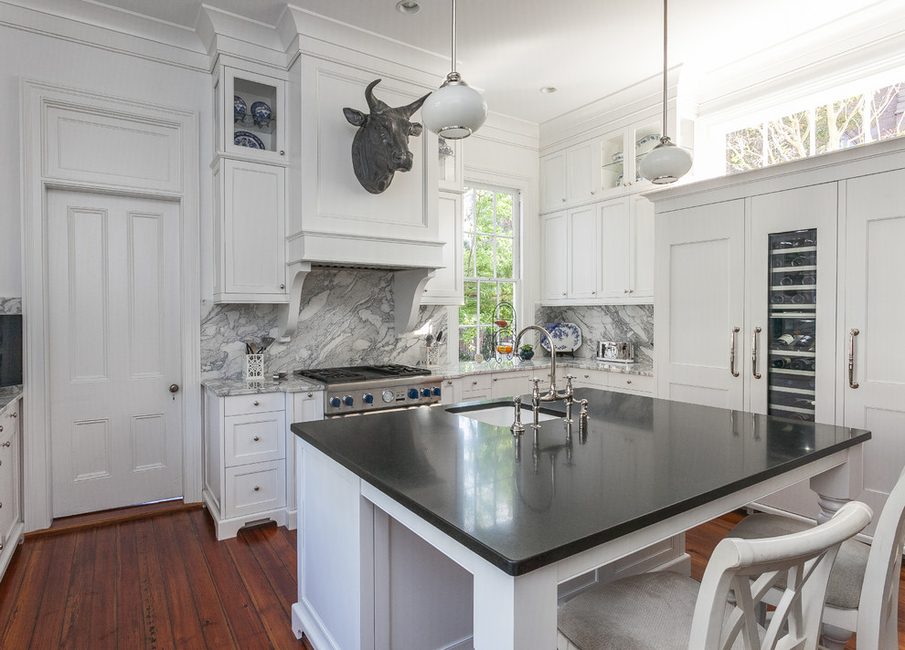 Inspiration pour une cuisine encastrable traditionnelle en U avec un évier encastré, un placard à porte shaker, des portes de placard blanches, une crédence blanche, parquet foncé et îlot.