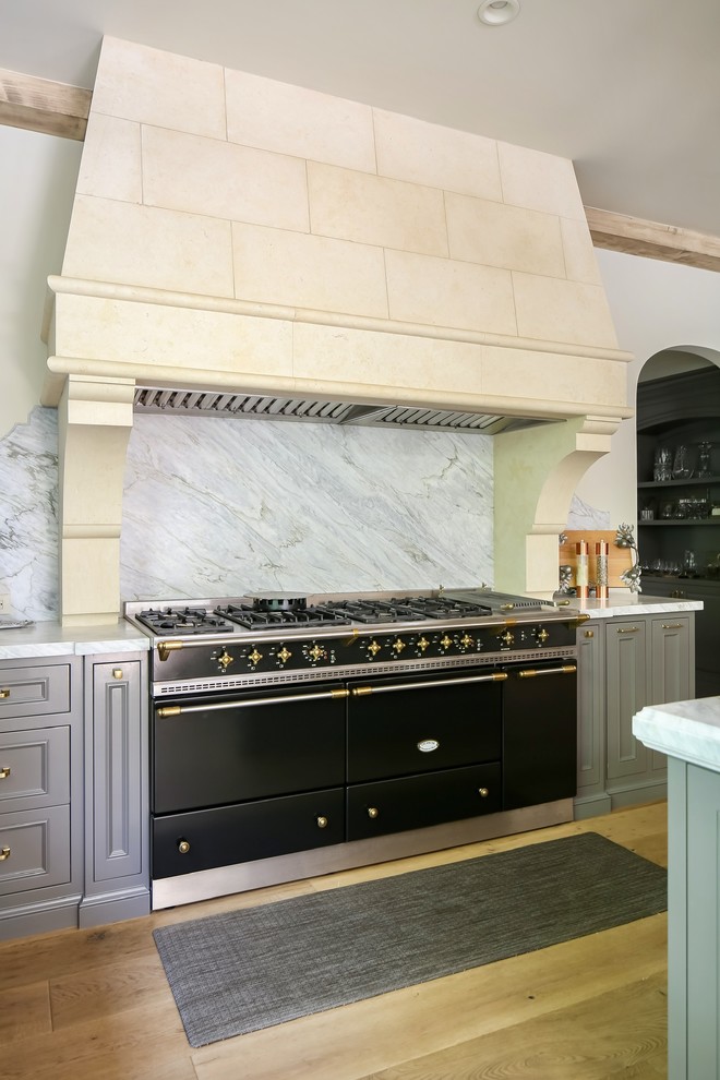 Exempel på ett mycket stort medelhavsstil vit vitt kök, med en undermonterad diskho, luckor med profilerade fronter, grå skåp, marmorbänkskiva, vitt stänkskydd, stänkskydd i marmor, integrerade vitvaror, ljust trägolv, en köksö och beiget golv