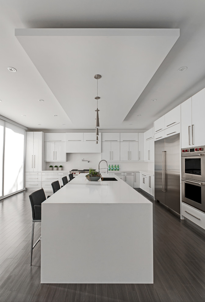 This is an example of a contemporary l-shaped kitchen in Toronto with a submerged sink, flat-panel cabinets, white cabinets, stainless steel appliances and an island.
