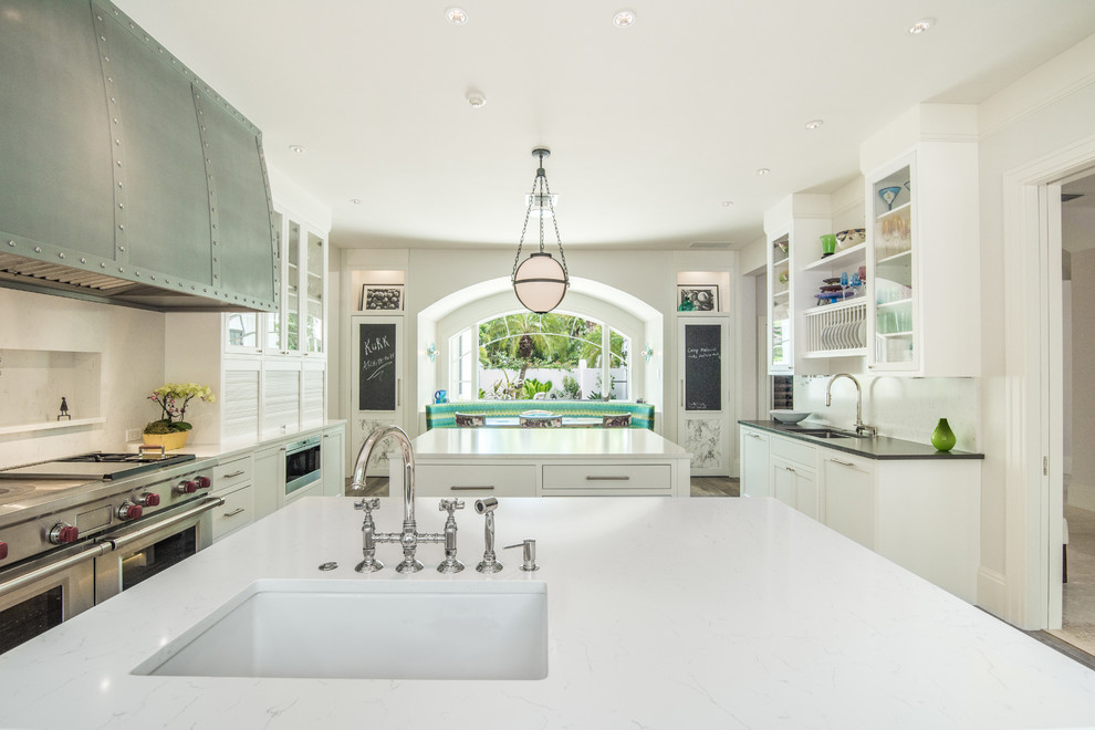 Photo of a world-inspired kitchen in Miami with flat-panel cabinets, white cabinets, granite worktops, white splashback, stainless steel appliances and medium hardwood flooring.