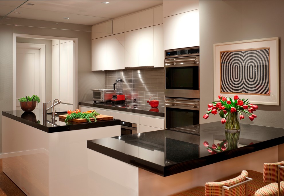 Imagen de cocina contemporánea con armarios con paneles lisos, puertas de armario blancas, salpicadero metalizado, salpicadero de metal y electrodomésticos de acero inoxidable