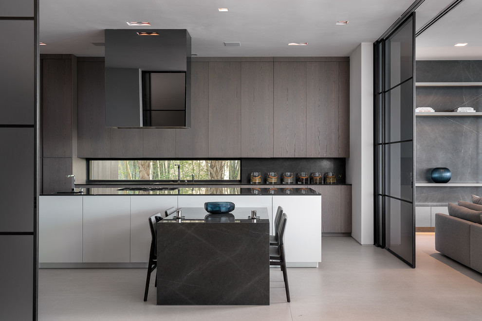 Cette image montre une grande cuisine encastrable minimaliste avec un placard à porte plane, des portes de placard marrons, un plan de travail en surface solide, sol en béton ciré, îlot, un sol gris et plan de travail noir.