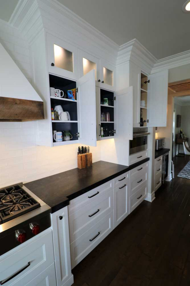 Inspiration for a large contemporary single-wall dark wood floor and brown floor kitchen pantry remodel in Los Angeles with a double-bowl sink, shaker cabinets, white cabinets, granite countertops, white backsplash, cement tile backsplash, stainless steel appliances, an island and black countertops