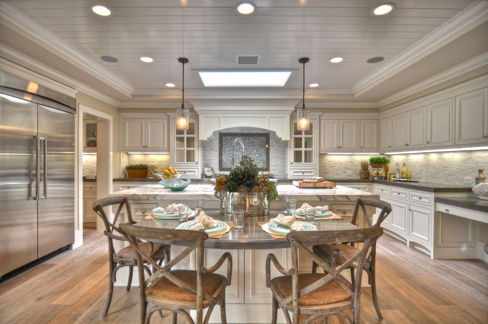 Beach style eat-in kitchen photo in Los Angeles with stainless steel appliances, recessed-panel cabinets and white cabinets