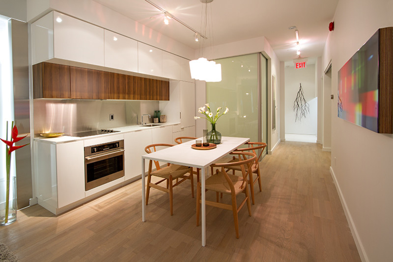 Small minimalist single-wall light wood floor eat-in kitchen photo in Toronto with an undermount sink, flat-panel cabinets, white cabinets, stainless steel appliances, an island and white countertops