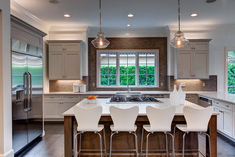 Transitional u-shaped kitchen photo in Orlando with a farmhouse sink, shaker cabinets, beige backsplash, stainless steel appliances and an island