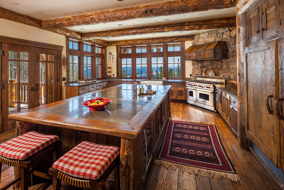 This is an example of an expansive rustic u-shaped kitchen in Other with stainless steel appliances, dark hardwood flooring and an island.