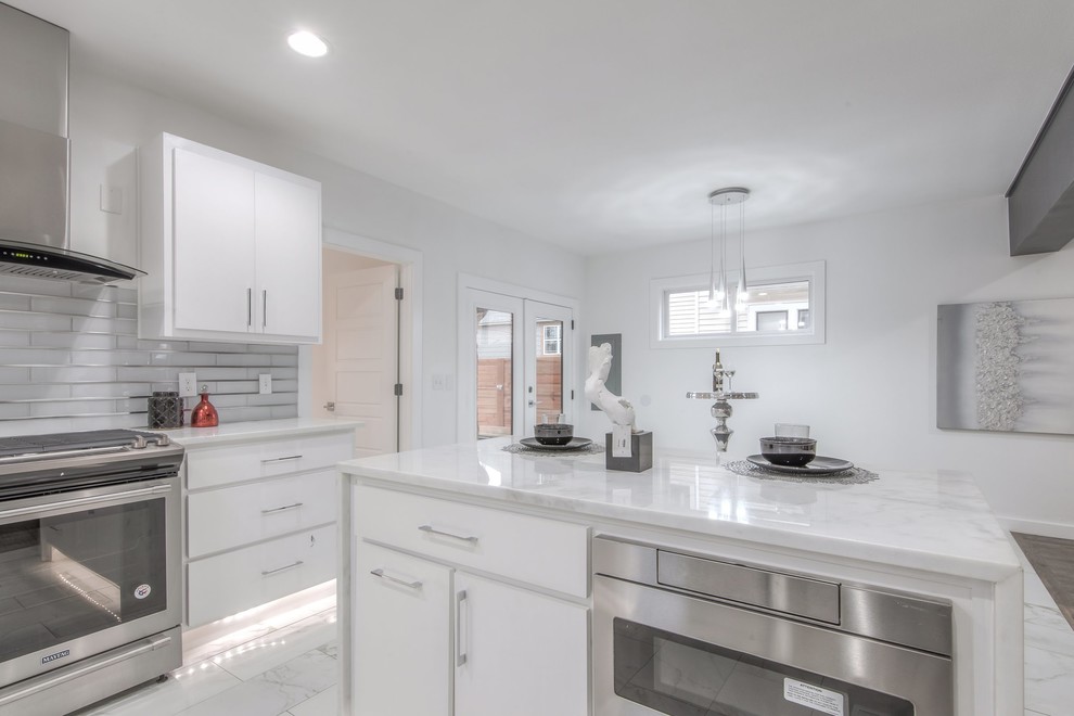Inspiration för stora moderna vitt kök, med en undermonterad diskho, släta luckor, vita skåp, marmorbänkskiva, stänkskydd med metallisk yta, stänkskydd i glaskakel, rostfria vitvaror, en köksö och vitt golv