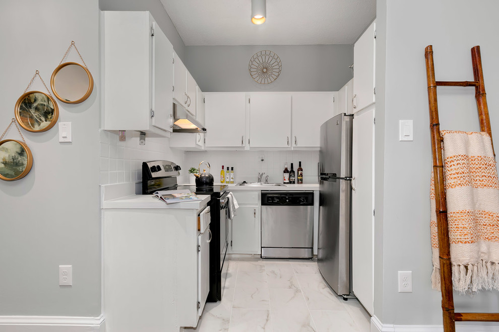 ワシントンD.C.にあるエクレクティックスタイルのおしゃれなコの字型キッチン (ドロップインシンク、フラットパネル扉のキャビネット、白いキャビネット、白いキッチンパネル、シルバーの調理設備、ベージュの床、白いキッチンカウンター) の写真